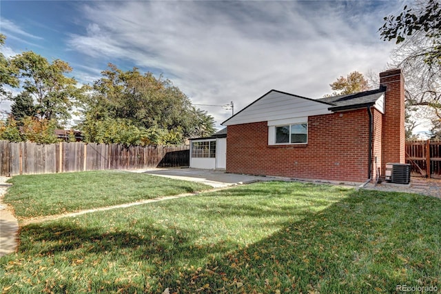 back of property featuring brick siding, a yard, a chimney, a patio, and a fenced backyard