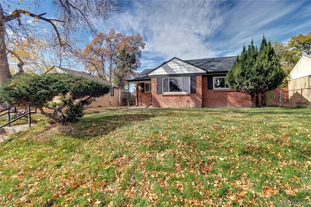 view of front of house featuring brick siding, fence, and a front lawn