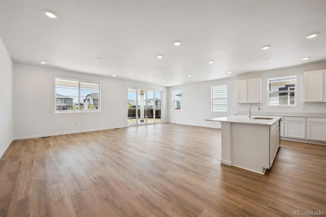 9061 Telluride Ct, Commerce City, CO 80022 - kitchen featuring a sink, recessed lighting, light wood finished floors, white cabinetry, and an island with sink