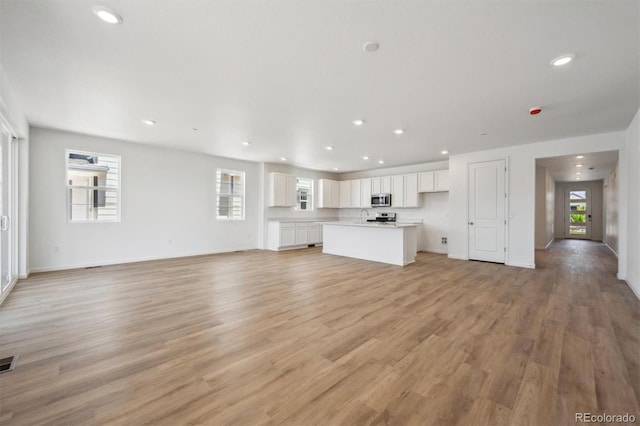 9061 Telluride Ct, Commerce City, CO 80022 - unfurnished living room with recessed lighting, light wood-style flooring, baseboards, and a sink