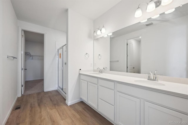 9061 Telluride Ct, Commerce City, CO 80022 - full bath featuring double vanity, a shower stall, wood finished floors, a spacious closet, and baseboards