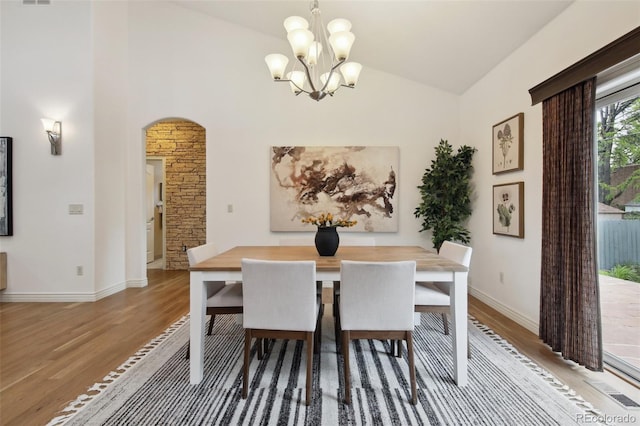1235 S Balsam St, Lakewood, CO 80232 - dining room featuring wood finished floors, arched walkways, lofted ceiling, a chandelier, and baseboards