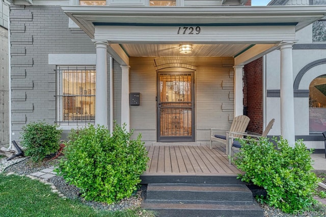 property entrance with a porch and brick siding