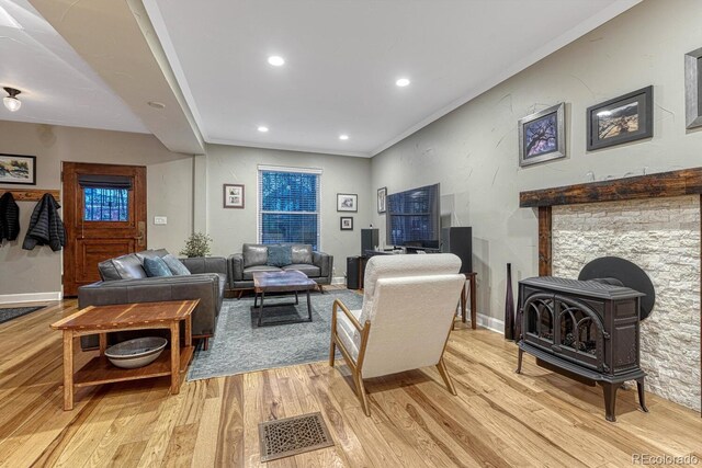 living area featuring a wood stove, light wood-style floors, baseboards, and recessed lighting
