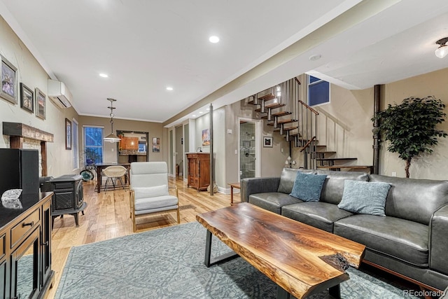 living area with recessed lighting, a wall mounted AC, baseboards, stairs, and light wood-type flooring