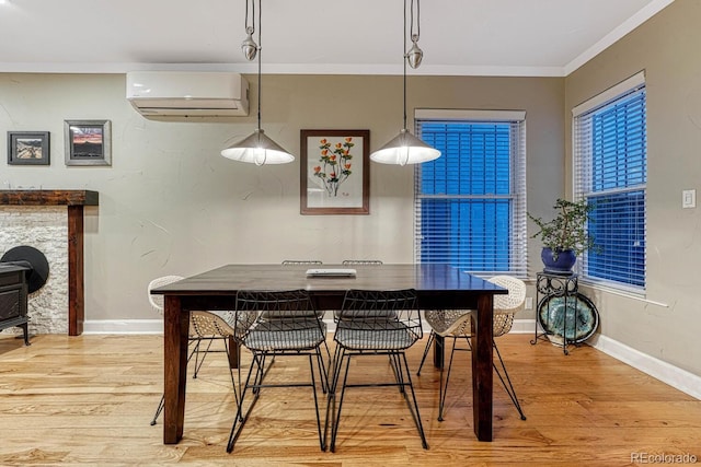 dining area with baseboards, light wood-style floors, ornamental molding, and a wall mounted AC