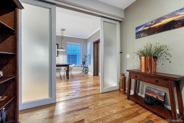 interior space with baseboards, ornamental molding, and light wood finished floors