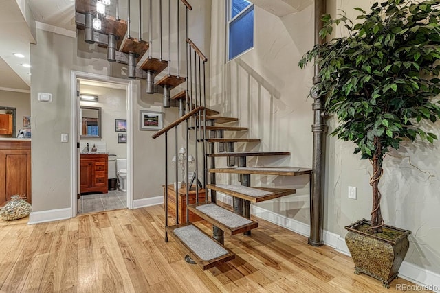 stairway with baseboards, crown molding, and wood finished floors