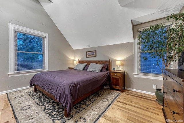 bedroom with lofted ceiling, baseboards, and light wood-style flooring