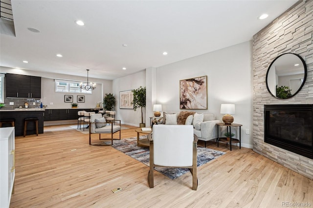 467 Harrison St, Denver, CO 80206 - living room featuring light wood-type flooring, a stone fireplace, a chandelier, and recessed lighting