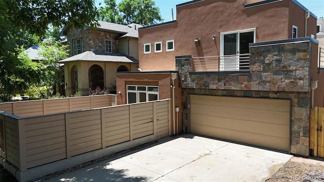 467 Harrison St, Denver, CO 80206 - rear view of property with a balcony, a garage, stucco siding, stone siding, and driveway