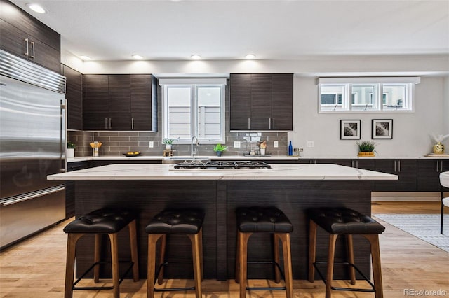467 Harrison St, Denver, CO 80206 - kitchen with stainless steel appliances, a breakfast bar area, modern cabinets, dark brown cabinetry, and backsplash
