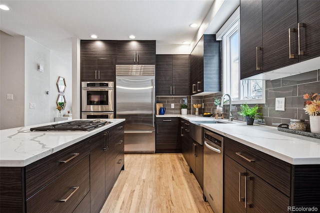 467 Harrison St, Denver, CO 80206 - kitchen with appliances with stainless steel finishes, light wood-type flooring, backsplash, dark brown cabinets, and recessed lighting