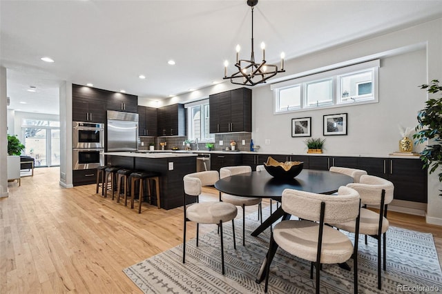467 Harrison St, Denver, CO 80206 - dining room with light wood finished floors, a chandelier, and recessed lighting