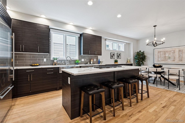 467 Harrison St, Denver, CO 80206 - kitchen featuring a breakfast bar area, a chandelier, tasteful backsplash, light wood finished floors, and recessed lighting