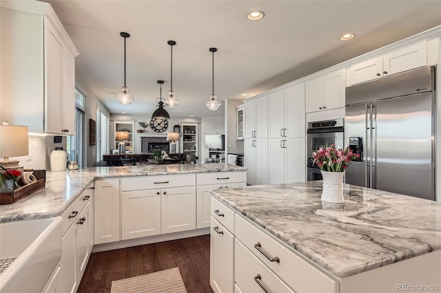 6013 S Kittredge Ct, Centennial, CO 80016 - kitchen featuring appliances with stainless steel finishes, dark wood finished floors, light stone counters, recessed lighting, and white cabinetry