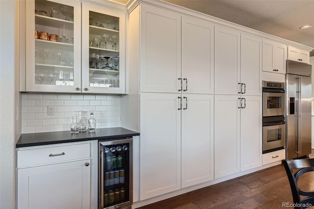 6013 S Kittredge Ct, Centennial, CO 80016 - bar with appliances with stainless steel finishes, beverage cooler, dark wood finished floors, decorative backsplash, and a bar