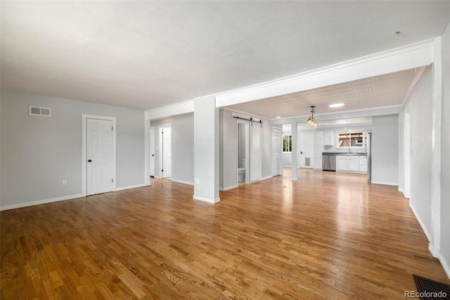 1406 N Foote Ave, Colorado Springs, CO 80909 - unfurnished living room featuring a barn door and light wood-type flooring