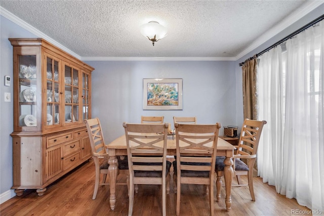 dining area with crown molding, a textured ceiling, and light wood-type flooring