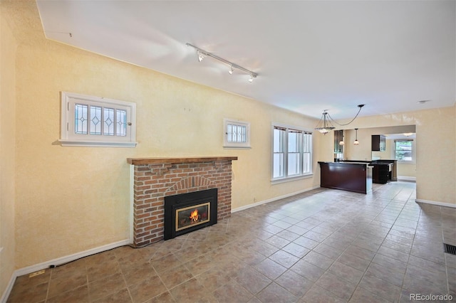 321 S Gilpin St, Denver, CO 80209 - unfurnished living room with rail lighting, a brick fireplace, and tile patterned flooring