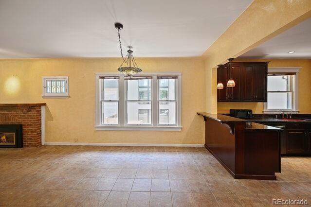 321 S Gilpin St, Denver, CO 80209 - kitchen with black microwave, a peninsula, decorative light fixtures, a fireplace, and open floor plan