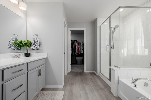 bathroom with wood-type flooring, vanity, and independent shower and bath