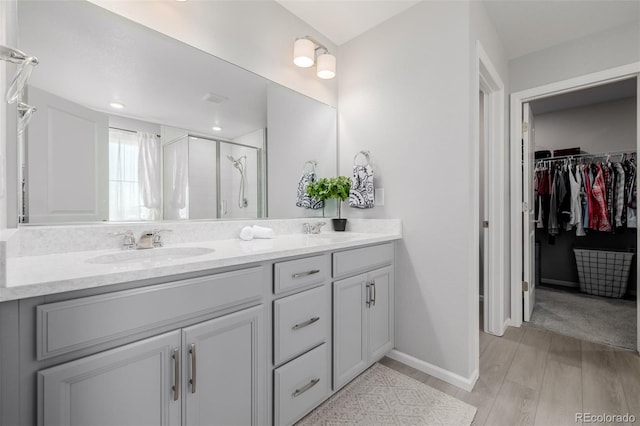 bathroom featuring a shower with shower door, hardwood / wood-style floors, and vanity