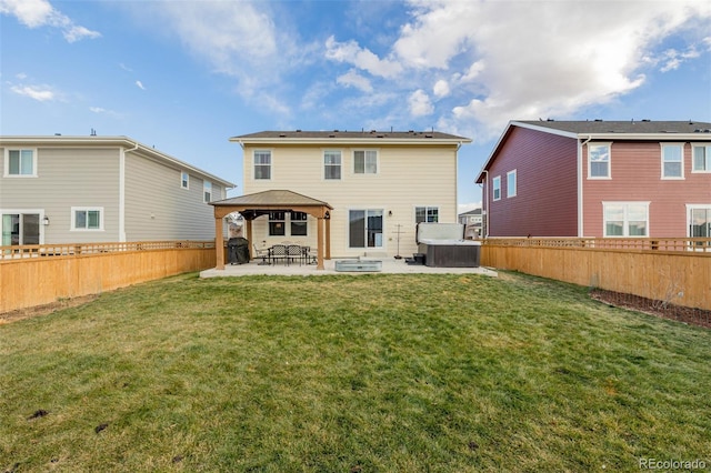 rear view of house with a lawn, a gazebo, a hot tub, and a patio area