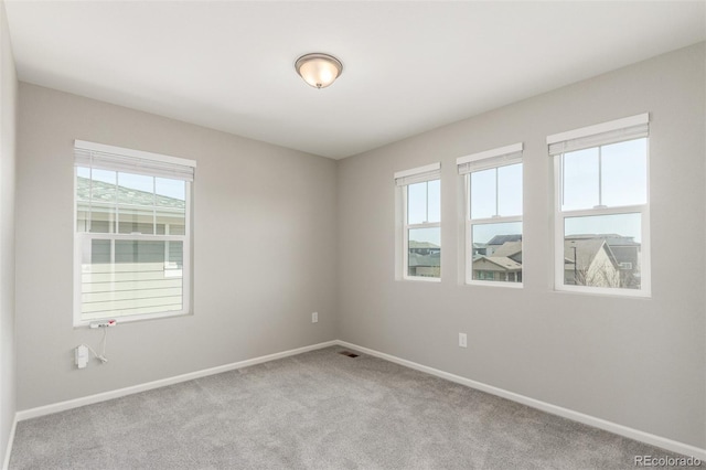 unfurnished room featuring visible vents, baseboards, plenty of natural light, and carpet