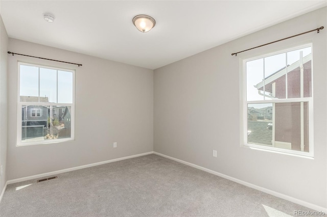 carpeted empty room with baseboards, visible vents, and a wealth of natural light
