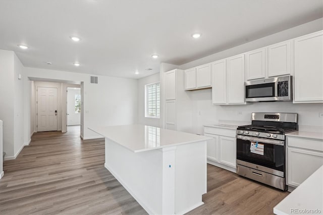 4246 Graywood Dr, Johnstown, CO 80534 - kitchen with appliances with stainless steel finishes, light wood finished floors, a center island, white cabinetry, and recessed lighting