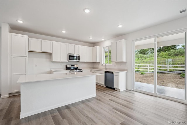 4246 Graywood Dr, Johnstown, CO 80534 - kitchen with appliances with stainless steel finishes, light countertops, white cabinets, light wood-type flooring, and a kitchen island
