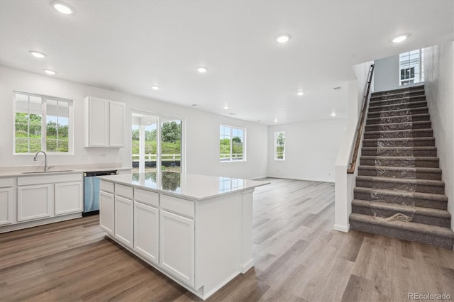 4246 Graywood Dr, Johnstown, CO 80534 - kitchen featuring a sink, stainless steel dishwasher, light wood-style flooring, white cabinets, and light countertops