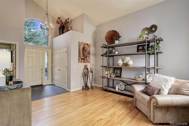 foyer entrance with high vaulted ceiling, wood-type flooring, and a chandelier