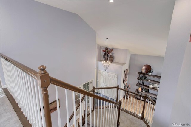 stairway featuring a chandelier, vaulted ceiling, and carpet