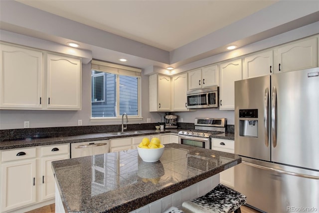 kitchen with white cabinets, stainless steel appliances, sink, and a kitchen island