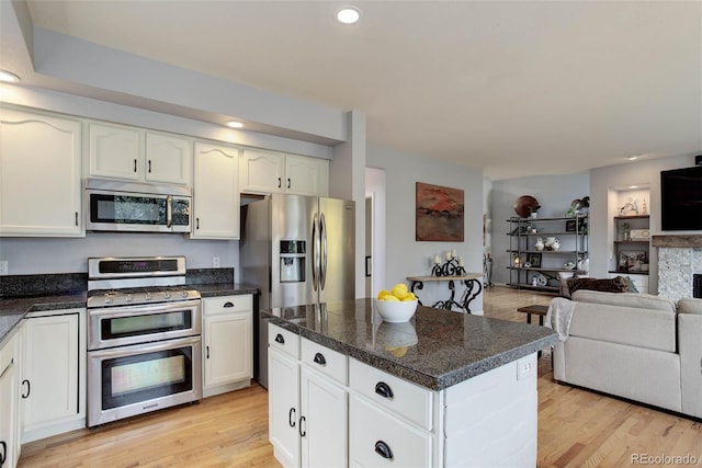 kitchen with appliances with stainless steel finishes, white cabinets, and light wood-type flooring