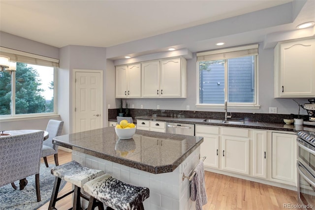 kitchen with sink, white cabinetry, stainless steel appliances, and light hardwood / wood-style floors