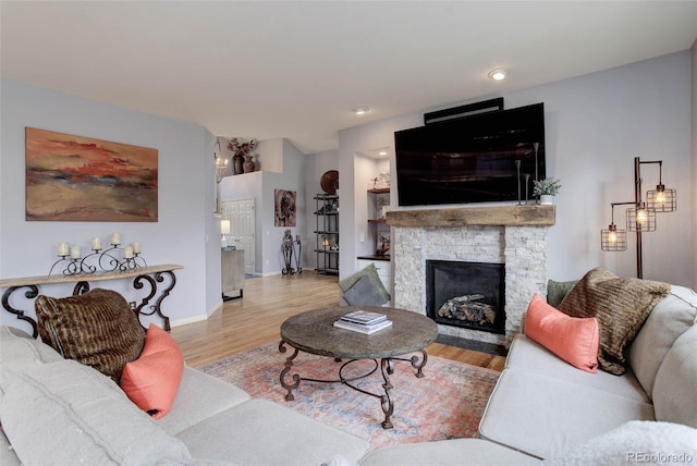 living room featuring a stone fireplace and light hardwood / wood-style floors