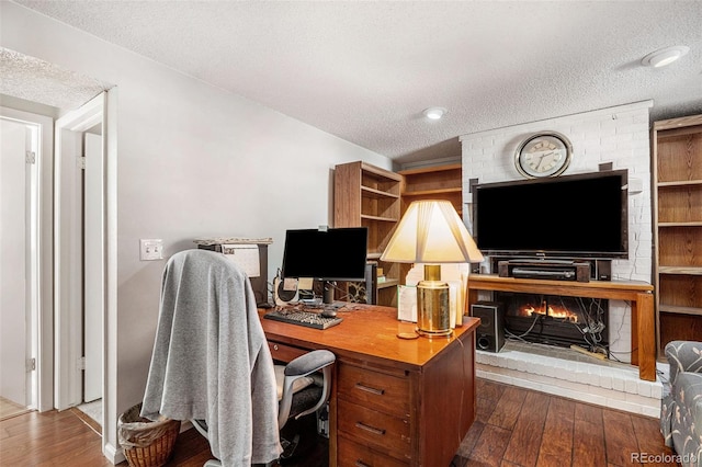 office featuring a textured ceiling, dark wood-type flooring, and a fireplace