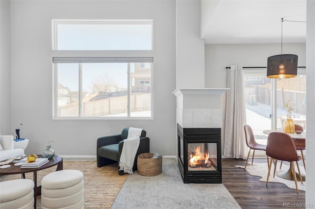 living room with a tiled fireplace, plenty of natural light, and dark hardwood / wood-style floors