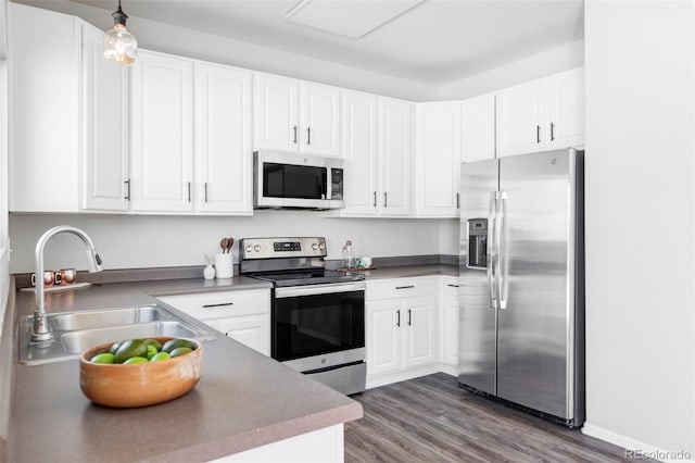 kitchen featuring white cabinetry, stainless steel appliances, sink, and hanging light fixtures