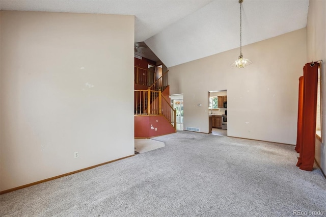 9908 Garfield Ct, Thornton, CO 80229 - unfurnished living room featuring high vaulted ceiling, light colored carpet, baseboards, and stairs