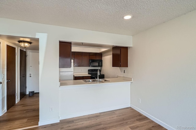 kitchen featuring black appliances, light countertops, a sink, and wood finished floors