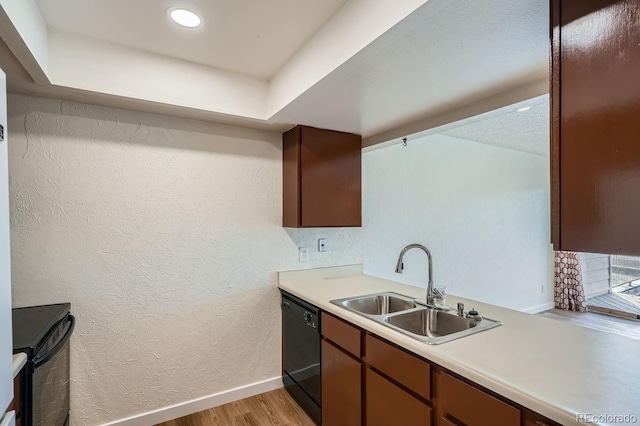 kitchen with a textured wall, a sink, light wood-style floors, light countertops, and dishwasher