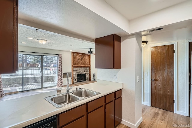 kitchen with dishwasher, light wood-style flooring, light countertops, a textured ceiling, and a sink