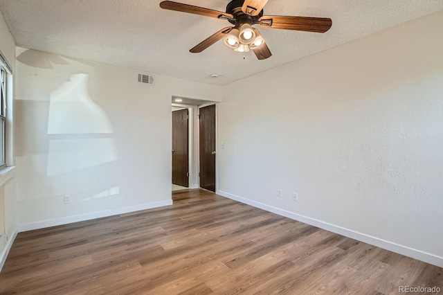 unfurnished room with baseboards, a textured ceiling, visible vents, and wood finished floors