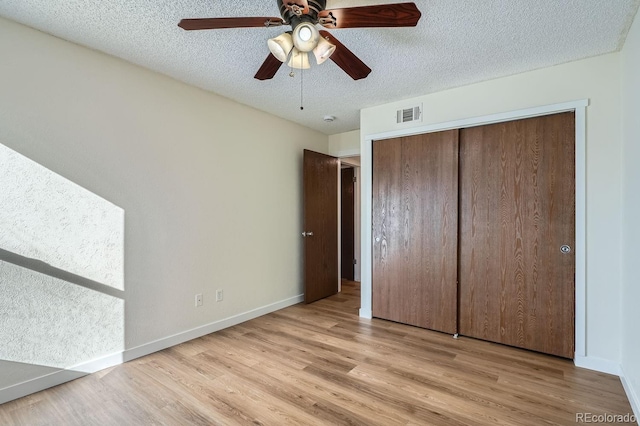 unfurnished bedroom featuring baseboards, light wood-style flooring, visible vents, and a textured ceiling