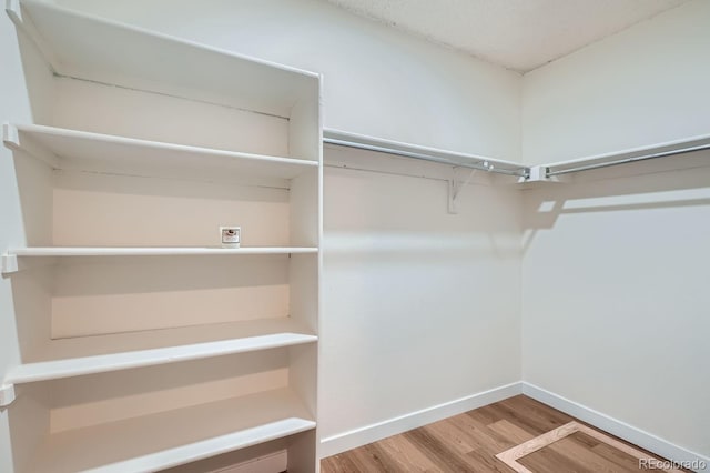 walk in closet with wood finished floors