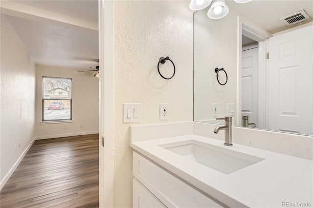 bathroom featuring baseboards, wood finished floors, visible vents, and vanity